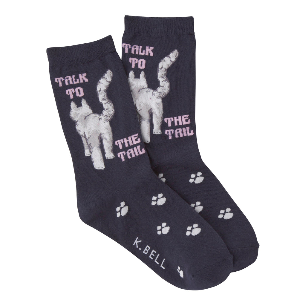 K Bell Talk to the Tail Sock is on a Navy. The Cat is Grey. Walking in the middle of words, "TALK TO THE TAIL". Paw Prints are on the Foot.