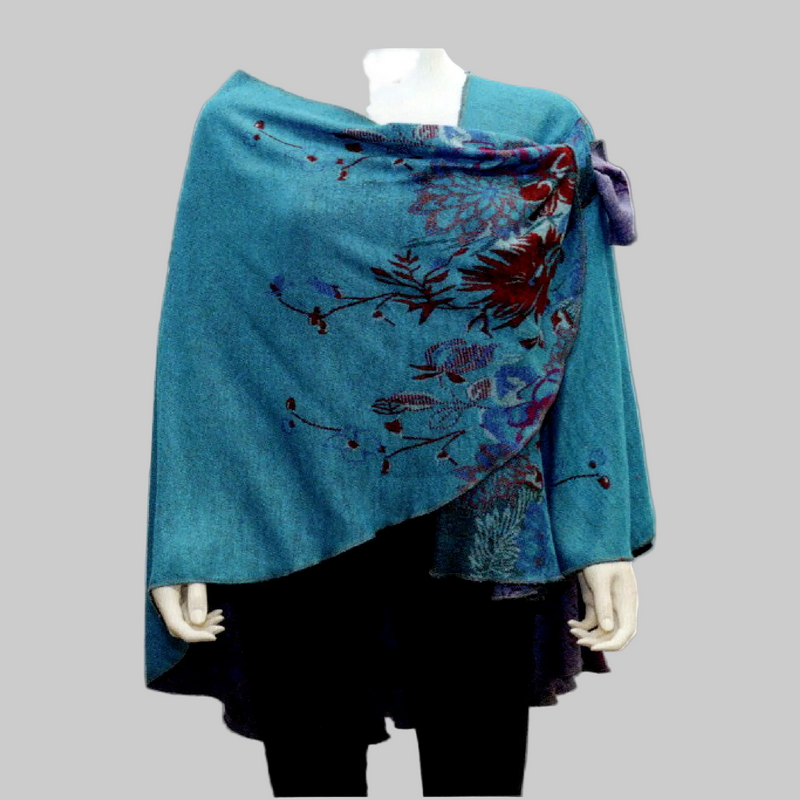 A teal blue shawl with red and purple floral embroidery, draped over a black dress on a mannequin against a white background.