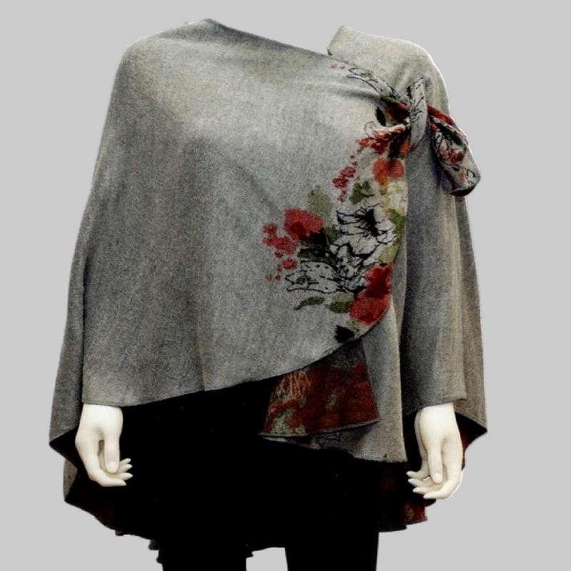 A gray shawl poncho with a red and green floral print draped over a black skirt, displayed on a white mannequin against a white background.