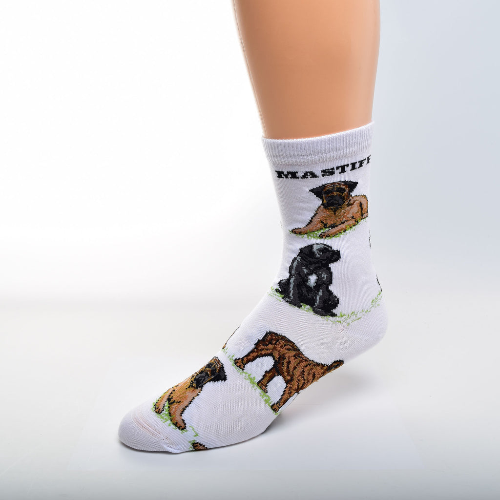 For Bare Feet Mastiff Poses Sock has a White background. Mastiff, is in Bold Black Print under the Cuff. The Poses are on Green Grass. The first Pose is an Apricot with Black Mask Mastiff Laying Down. Then a Black Mastiff with White Markings Sitting.  A Brindle Mastiff in a Stance is the Last and the pattern begins to repeat.