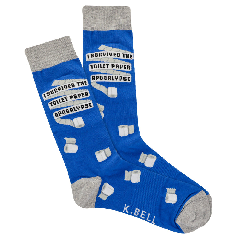 K Bell Mens Toilet Paper Sock begins on a Royal Blue background  and Heathered Charcoal Grey at the Cuffs, Heels and Toes. The Toilet Paper is Unfurled for the words to be written. "I SURVIVED THE TOILET PAPER APPOCALYPSE." Toilet Paper Rolls are scattered over the Sock.  